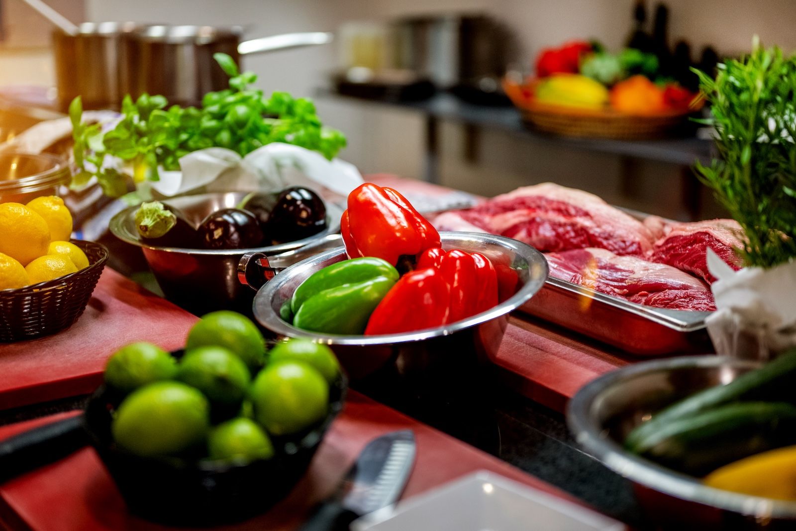 Frisches Gemüse wie Paprika, Auberginen, Zitronen und Kräuter liegt neben hochwertigem Fleisch bereit – eine bunte Auswahl für die Zubereitung kreativer Gerichte.